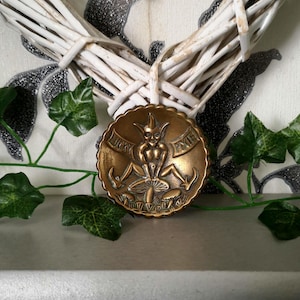 May include: A brass trinket dish featuring a raised design of a pixie sitting on a mushroom. The pixie is holding a staff and has a mischievous expression. The words "Lucky Pixie" are inscribed around the edge of the dish.