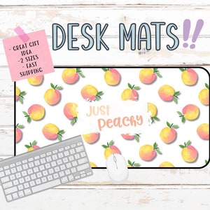 Puede incluir: Una alfombrilla de escritorio blanca con un patrón de melocotón y el texto "Just Peachy". Un teclado y un ratón están sobre la alfombrilla.