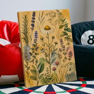 May include: A rectangular canvas print featuring a botanical illustration of various herbs and wildflowers, including chamomile, lavender, and sage, set against a warm, textured yellow background with watercolor-style washes and fine ink details.