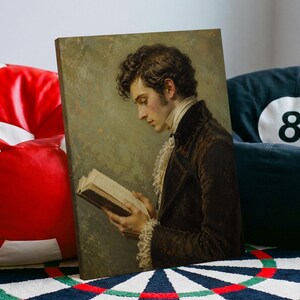 Op de afbeelding: Een canvasprint met een portret van een persoon met donker golvend haar, gekleed in een donkerbruine jas met een hoge kraag en een witte kanten bef, die een open boek vasthoudt. De achtergrond is een gedempt, getextureerd olijfgroen vlak.