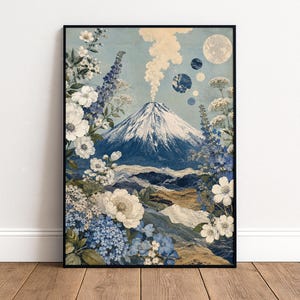 May include: A rectangular canvas wall art print featuring a central snow-capped mountain with a plume of smoke rising from the peak. The scene is framed by detailed blue and white floral illustrations, with a moon and small circular planets above.
