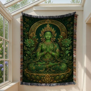 May include: A woven wall tapestry featuring a green-skinned deity in a meditative pose with hands pressed together. The figure wears an ornate gold crown and jewelry, seated on a lotus throne surrounded by green floral patterns and gold accents.