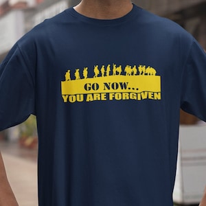 May include: Navy blue t-shirt with a yellow rectangular design. The design features a line of silhouetted figures above the text "GO NOW... YOU ARE FORGIVEN" in yellow. The shirt is made of a soft material.