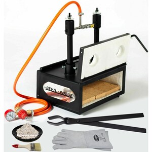 May include: Black metal forge with a white ceramic door and a red and orange gas hose. The forge is labelled "Devil Forge". The image also shows a pair of tongs, a pair of leather gloves, a small bowl of refractory mortar, and a paintbrush.