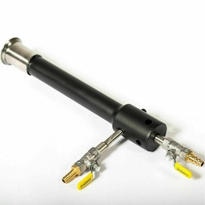 May include: A black metal burner with two valves and yellow handles. The burner has a stainless steel connector on one end.