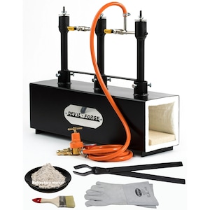 May include: A black metal forge with two orange gas burners and a white refractory lining. The forge comes with a set of tools including tongs, gloves, a brush, and refractory mortar.