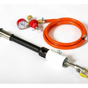 Puede incluir: Una antorcha negra y plateada con un mango blanco y plateado, un manómetro rojo y plateado y una manguera naranja. La antorcha se utiliza para calentar y soldar.