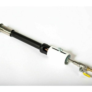 May include: A black and silver gas burner with a white ceramic tube and a yellow valve. The burner is designed for outdoor use and can be used to heat a variety of items.