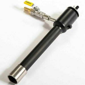 Puede incluir: Un soplete de metal negro con una punta plateada y una manija de válvula amarilla. El soplete está conectado a un tubo de metal negro con una punta plateada.