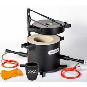 Puede incluir: Un horno de metal negro con un revestimiento refractario blanco y una tapa de metal negro. El horno tiene un soporte de metal negro y un asa de metal negro. El horno está etiquetado como "Jewel Forge". El horno se acompaña de un crisol negro etiquetado como "20KG", un par de guantes de soldadura de cuero naranja y dos mangueras naranjas.