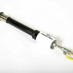 May include: A black and silver gas burner with a white valve and a yellow handle. The burner has a long, cylindrical body and a round, white base.