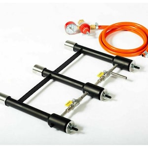 Puede incluir: Un quemador de propano de metal negro con tres válvulas ajustables y un manómetro. El quemador está conectado a una manguera naranja larga.