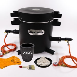 May include: A black metal Devil-Forge furnace with attached gas lines and a crucible labeled "20KG." Included are safety gloves, a brush, and refractory mortar. The furnace has a cylindrical body and a flat top.