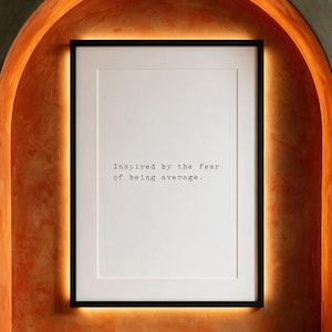 Framed black and white typographic ambition print within a backlit persimmon plaster arch.