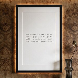 Framed black typographic dry wit print against a book-matched olive ash burl wall with a marble console.