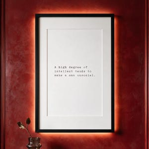 Framed black and white typographic introvert print on a carmine panelled wall above a dark walnut console.