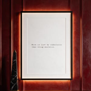Framed typographic decision making print on a carmine panelled wall above a walnut console.