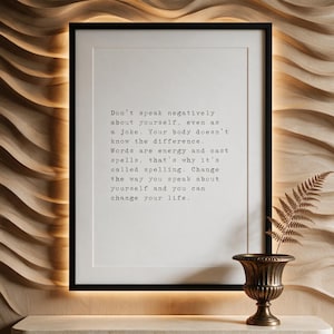 Framed black and white typographic self talk print on a carved pale oak wave wall above a travertine console.