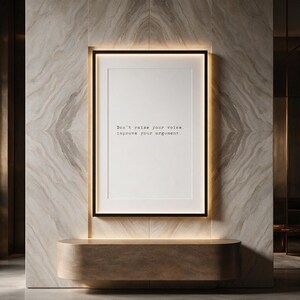 Framed black and white typographic debate print in a backlit pale travertine niche.