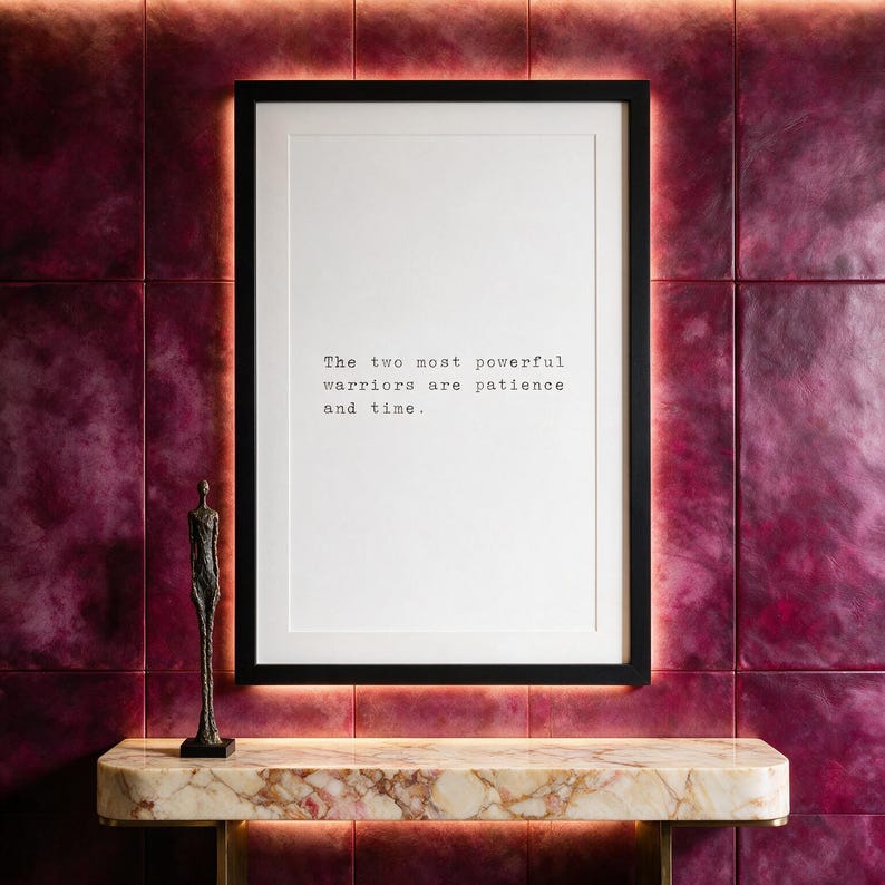 Framed black and white typographic stoic print on a magenta hand-dyed leather panelled wall above a cream marble console.