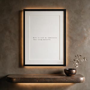 Framed black and white typographic decision making print on a taupe limewashed wall above a stone console.