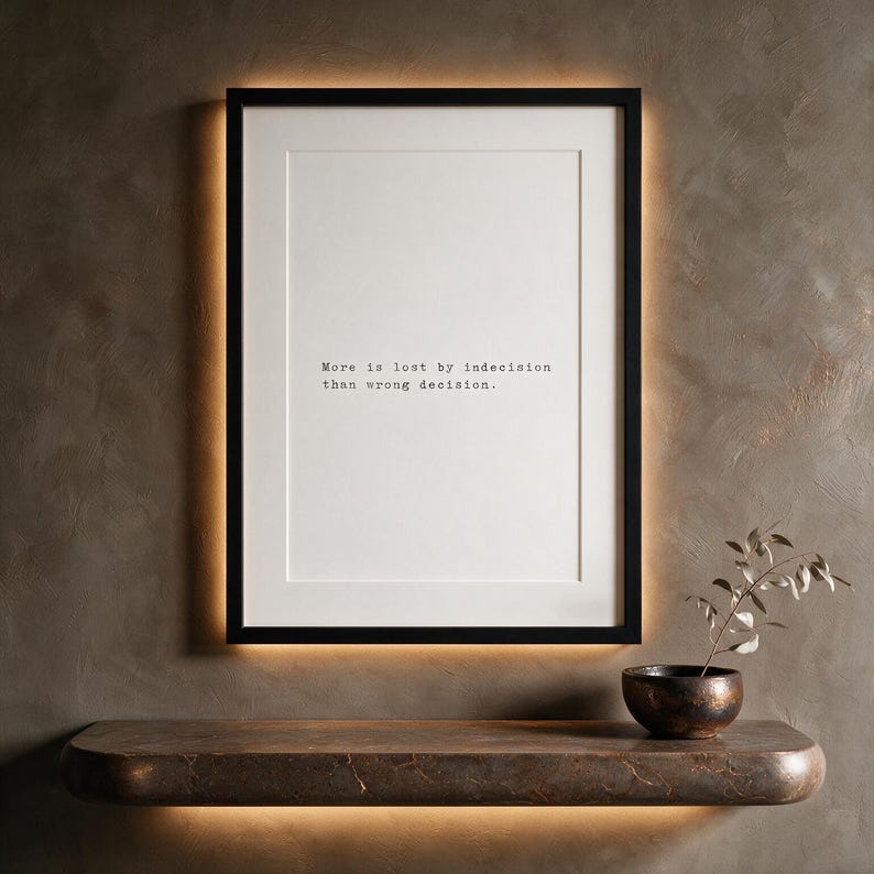 Framed black and white typographic decision making print on a taupe limewashed wall above a stone console.