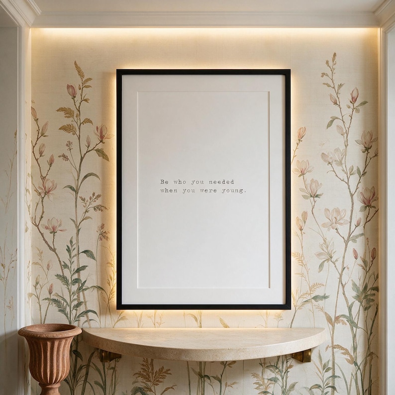 Framed black and white typographic healing print on a hand-painted botanical wall above a stone console.