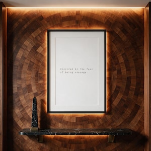 Framed typographic ambition print on a radial marquetry wall above a marble console.