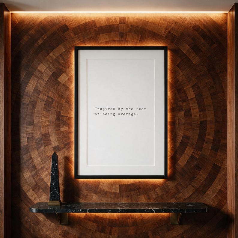 Framed typographic ambition print on a radial marquetry wall above a marble console.
