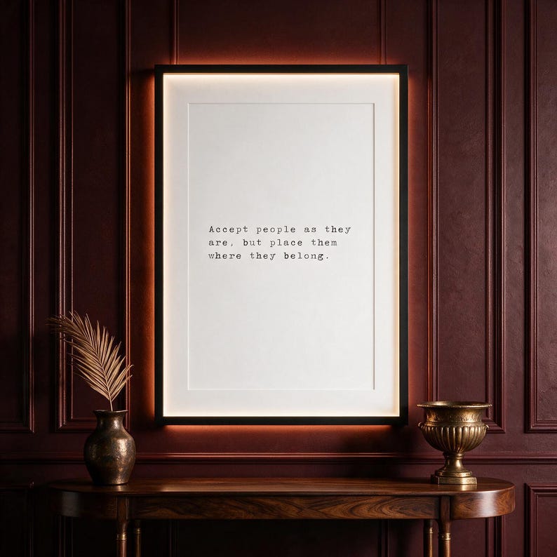 Framed typographic philosophy print on a deep oxblood panelled wall above a dark walnut console with brass planter.
