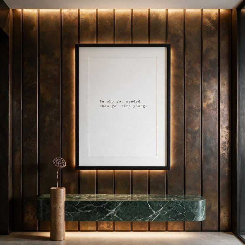 Framed typographic healing print on a patinated bronze panelled wall above a marble console.