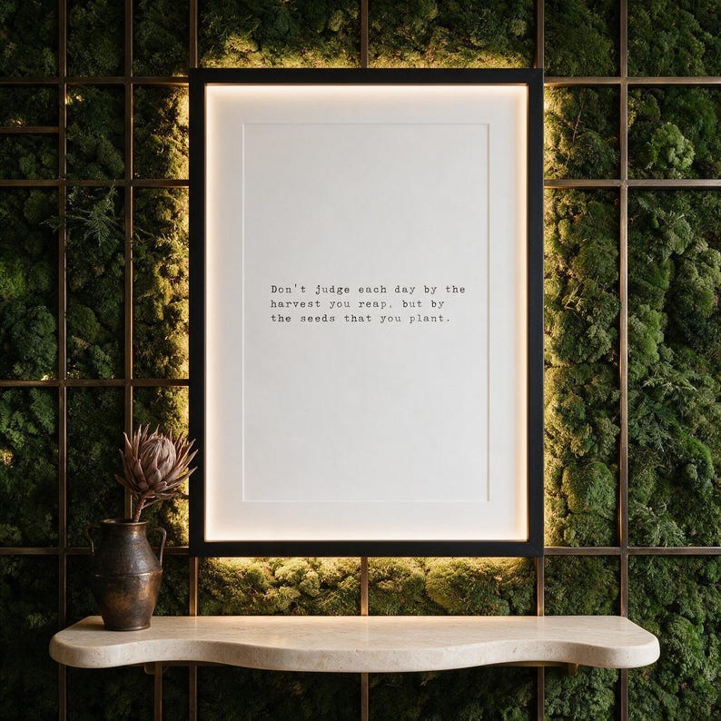 Framed black and white typographic growth print on a full moss wall above a travertine console.