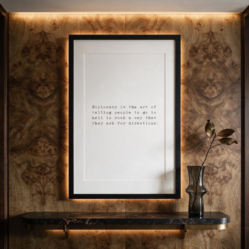 Framed black typographic dry wit print against a book-matched olive ash burl wall with a marble console.