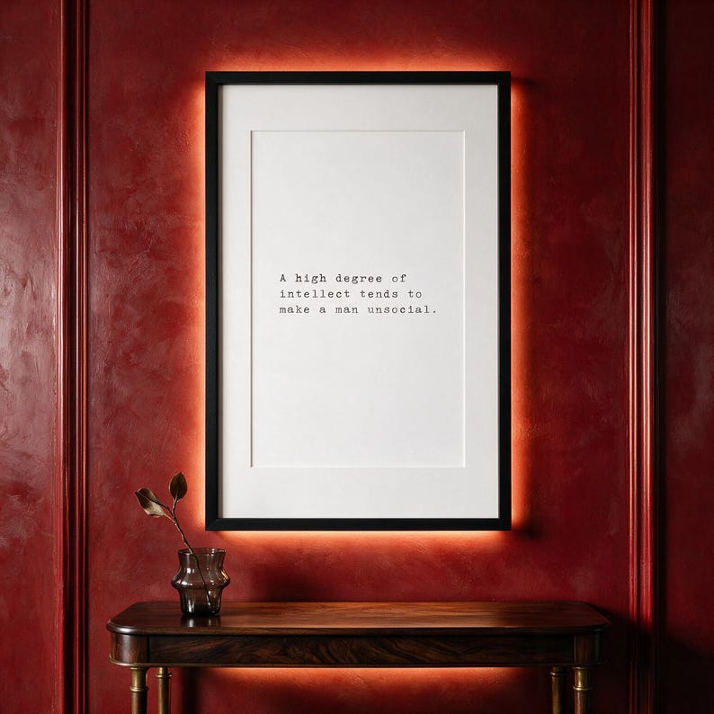 Framed black and white typographic introvert print on a carmine panelled wall above a dark walnut console.