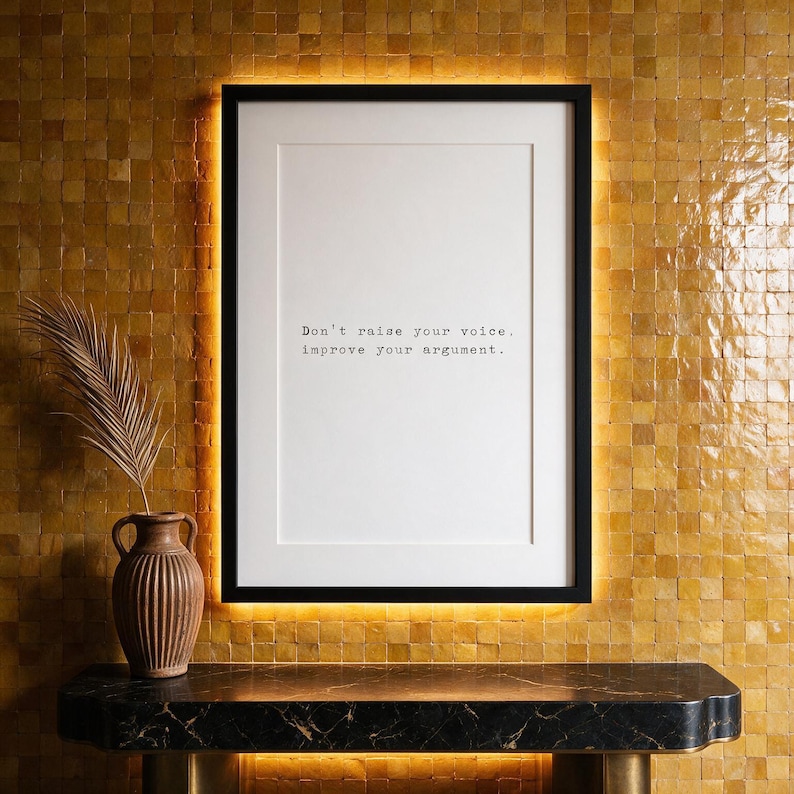 Framed typographic debate print on a glazed zellige tile wall above a marble console.