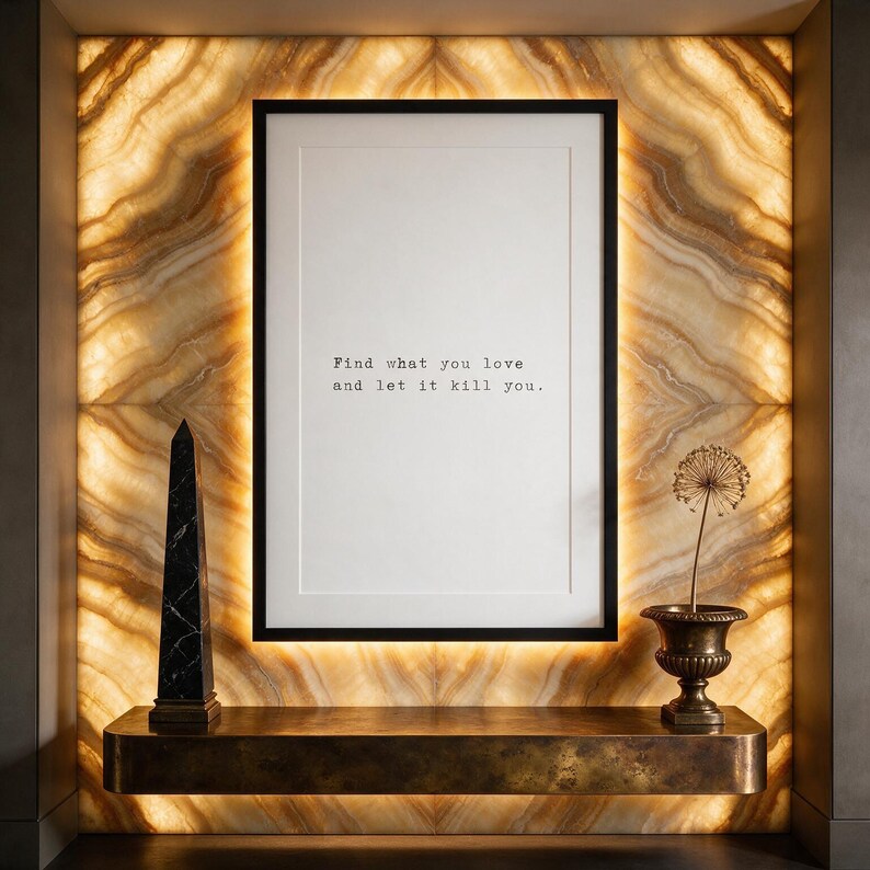 Framed typographic philosophy print on a backlit honey onyx wall above a patinated bronze console.