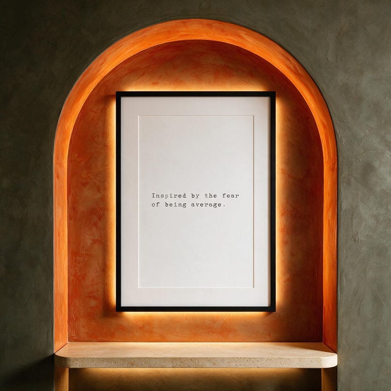 Framed black and white typographic ambition print within a backlit persimmon plaster arch.