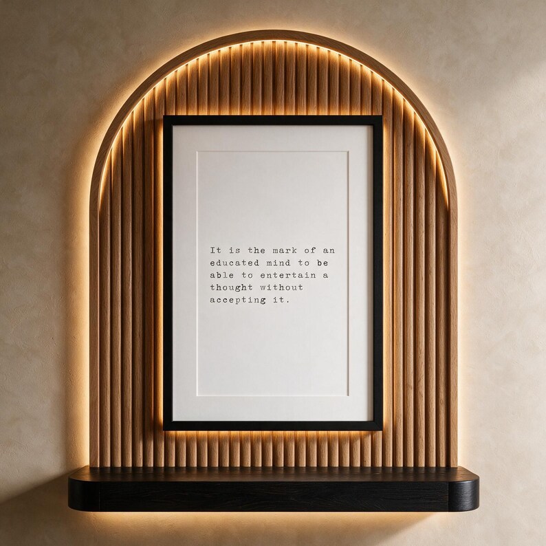 Framed black and white typographic philosophy print in a backlit fluted oak arch above an ebonised oak console.