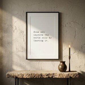 Puede incluir: Una l&aacute;mina de arte enmarcada con fondo blanco y texto negro estilo m&aacute;quina de escribir que dice: Some men improve the world only by leaving it. La impresi&oacute;n est&aacute; dentro de un marco negro fino, mostrando una cita clara y legible.