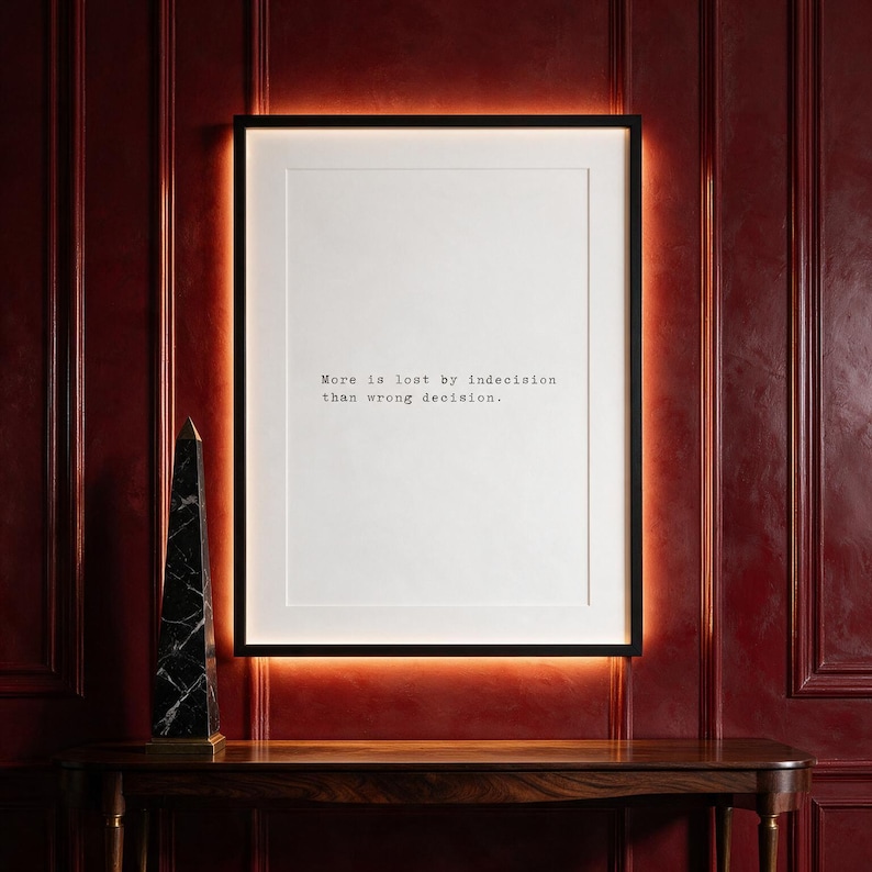 Framed typographic decision making print on a carmine panelled wall above a walnut console.