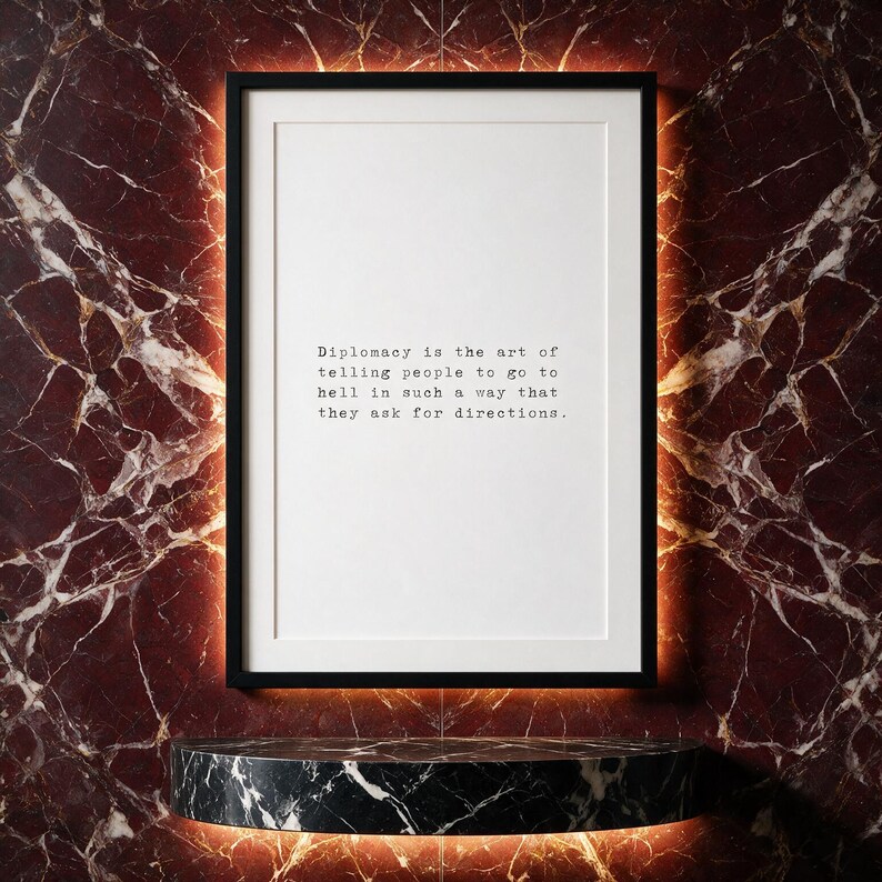 Typography quote print in a black frame set against deep claret book-matched marble with a backlit niche.