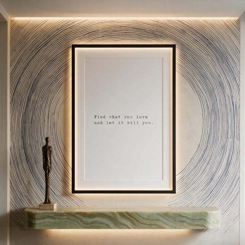 Framed black and white typographic philosophy print on a hand-painted contour mural wall above a pale marble console.