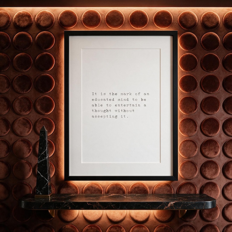 Framed typographic philosophy print on a terracotta velvet medallion wall above a dark marble console.