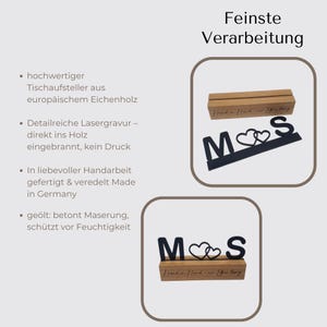 May include: A wooden table display with the letters "M" and "S" and two heart symbols, with a wooden base. The display is black and brown, with the text "Hand in Hand - for a long time" on the base. The text "Finest Processing" is at the top.