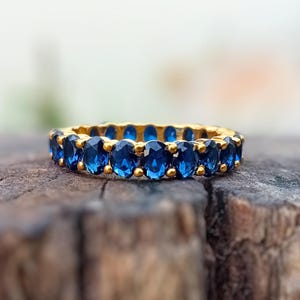 Könnte beinhalten: Ein Goldring mit einer Reihe blauer ovaler Edelsteine.
