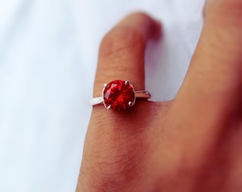 Peut inclure: Une bague en argent avec une grosse pierre rouge ronde.
