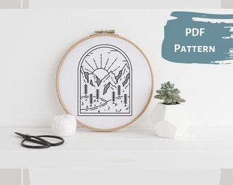 May include: Black and white line art embroidery pattern of a mountain landscape with a sun rising over the peaks. The pattern is in a hoop and is ready to be stitched.