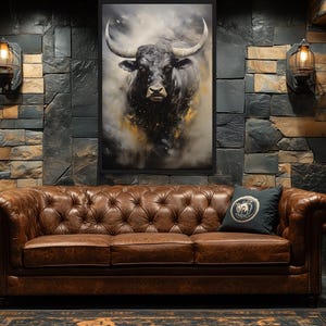 a large, brown leather couch with a tufted design, positioned in front of a stone wall with a framed picture of a bull's head hanging above it. The room also includes a wooden barrel, a lamp, and a rug on the floor.