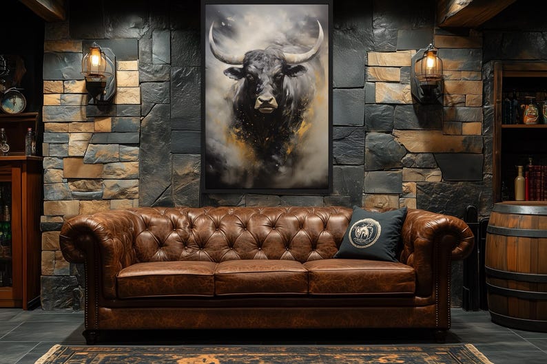 a large, brown leather couch with a tufted design, positioned in front of a stone wall with a framed picture of a bull's head hanging above it. The room also includes a wooden barrel, a lamp, and a rug on the floor.