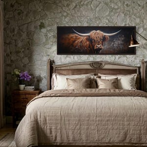 a bedroom with a large bed, a framed painting of a horned animal, and a lamp on a nightstand.